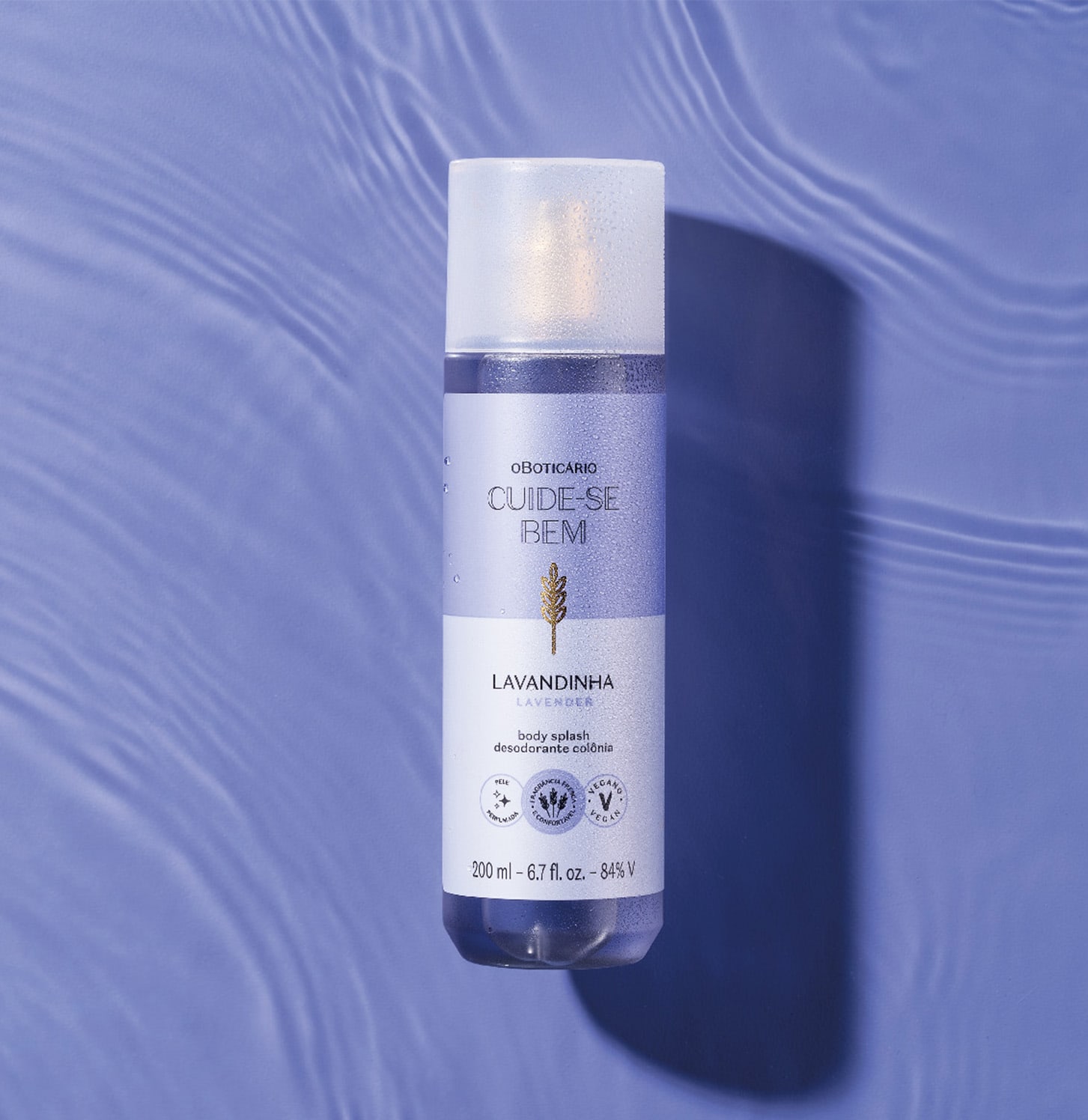 Frasco branco de item de perfumaria da marca Cuide-se bem, com rótulo roxo e dourado, sobre superfície azul com reflexos ondulados.