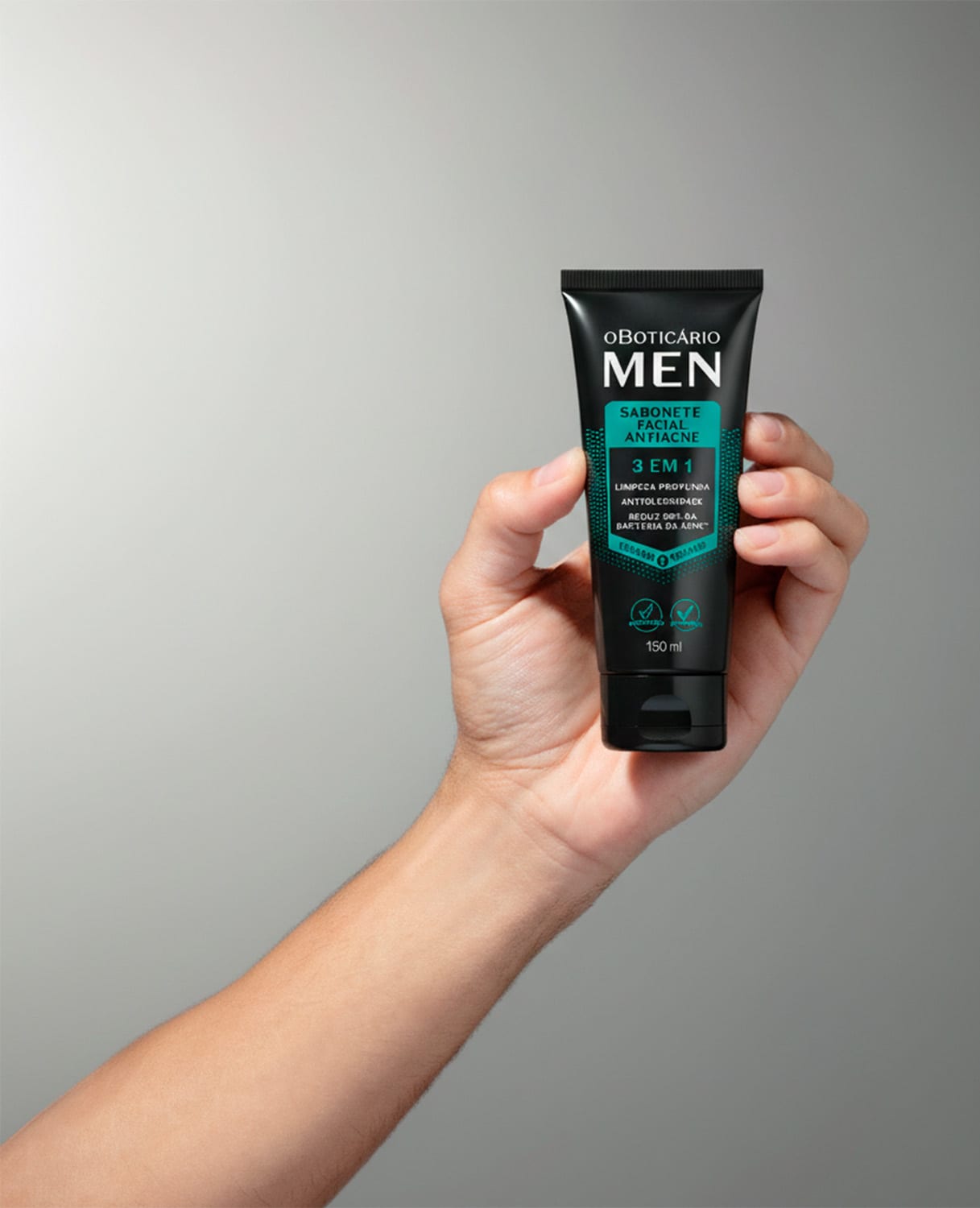 Imagem da embalagem do sabonete líquido facial Men com embalagem preta e verde, apresentado em uma mão contra um fundo neutro, sugerindo um ambiente minimalista e focado no produto.