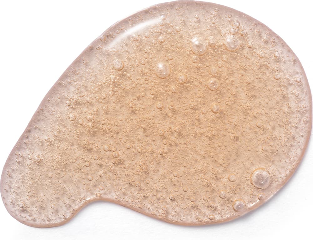 Textura do sabonete líquido Cuide-se Bem Deleite Caramelizado com aspecto granulado, brilhante e úmido, com pequenas bolhas distribuídas uniformemente sobre uma superfície clara.