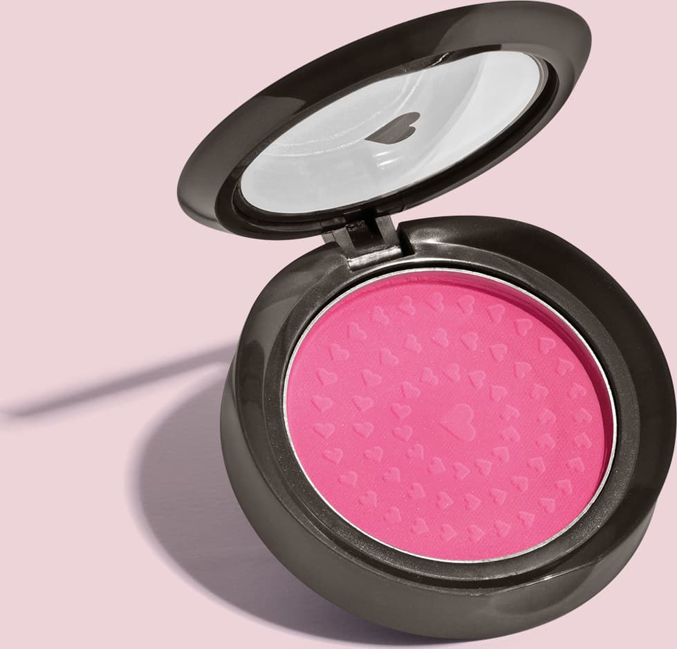 Estojo compacto redondo na cor preta com tampa transparente com coração ilustrado contendo 2g de blush em pó compacto Rubor Rosa Rosandilex da marca Quem Disse, Berenice? em fundo lilás.