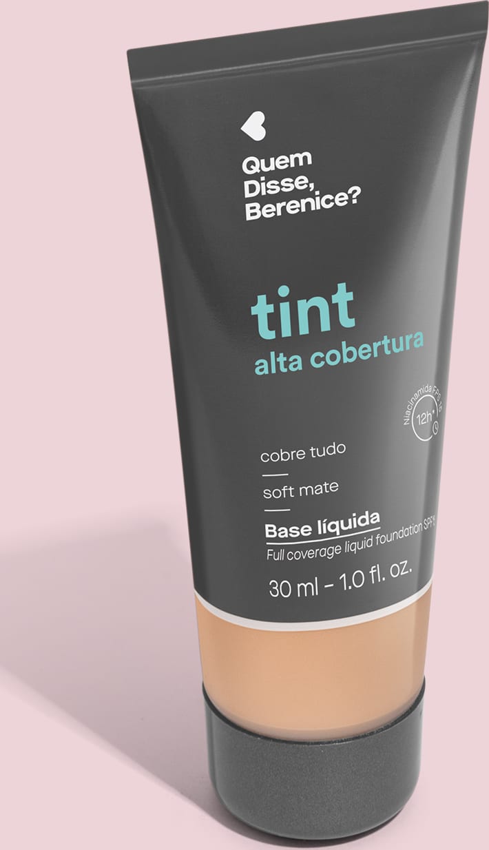 A imagem mostra a Base Tint Alta Cobertura da Quem Disse, Berenice? Embalagem preta com parte inferior transparente para mostrar a cor. O texto com nome e benefícios do produto aparece em letras brancas e em turquesa sobre fundo preto.