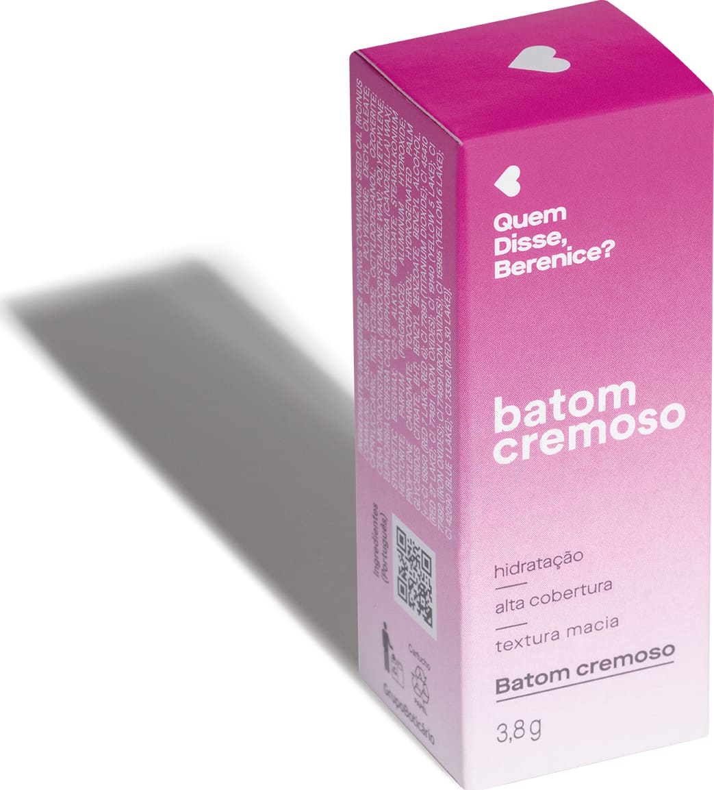 Caixa rosa com coração branco, contendo texto "Quem disse, Berenice?" e "Batom cremoso" em embalagem de 3,8g. A iluminação do ambiente forma uma longa sombra projetada atrás da embalagem.