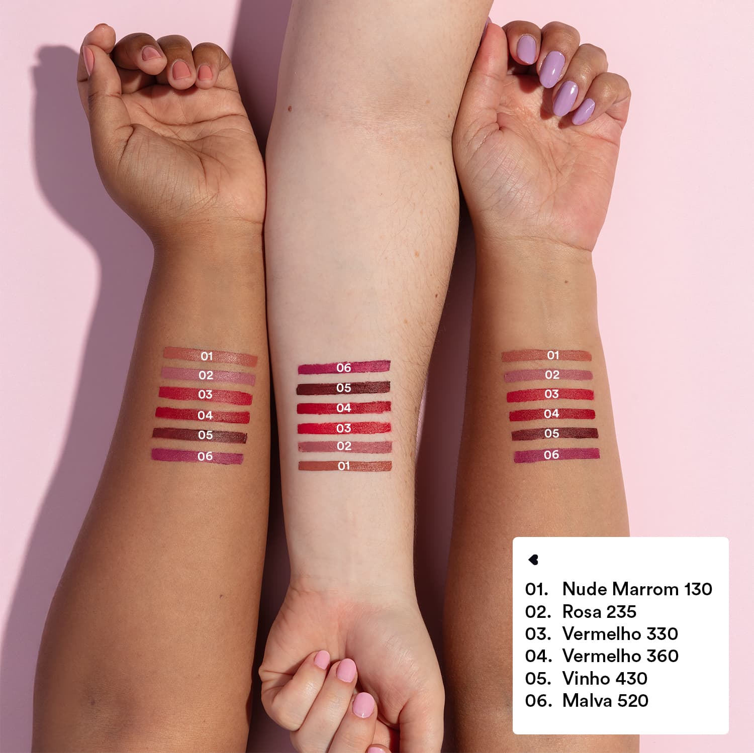 Imagem mostra três braços de cores diferentes estendidos sobre superfície rosada, sendo um de pele negra, um de pele branca e um de pele parda, todos com diversos tons de batons aplicados sobre eles e seus códigos.