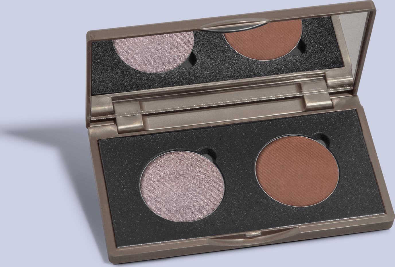 Paleta de sombras da marca Quem Disse, Berenice? com tom de prata e marrom em embalagem retangular preta e espelho na tampa em fundo azul claro com sombras.