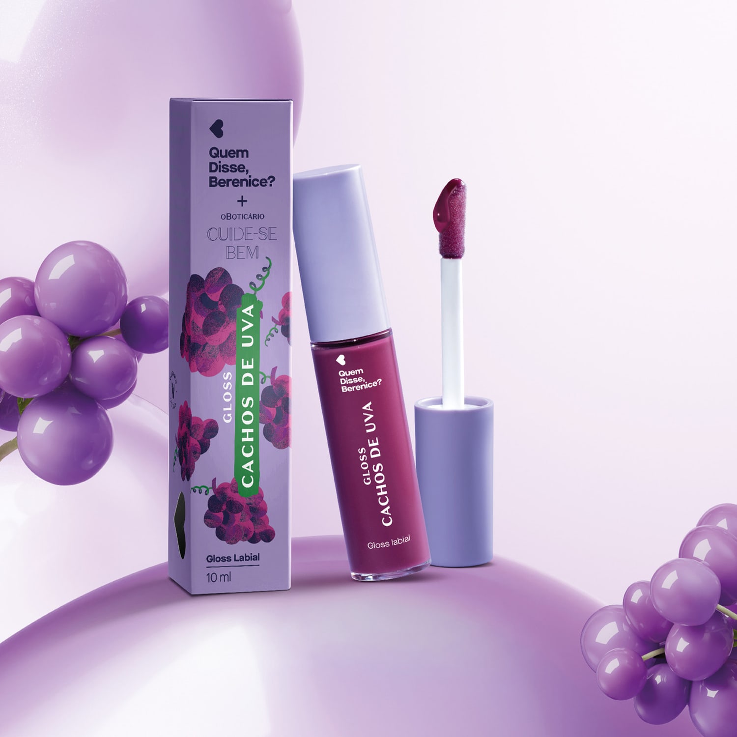 Imagem de embalagem de gloss labial da marca Quem Disse, Berenice? com o frasco do gloss em tom de roxo ao lado 
rodeada por balões e uvas roxas em um ambiente monocromático lilás.