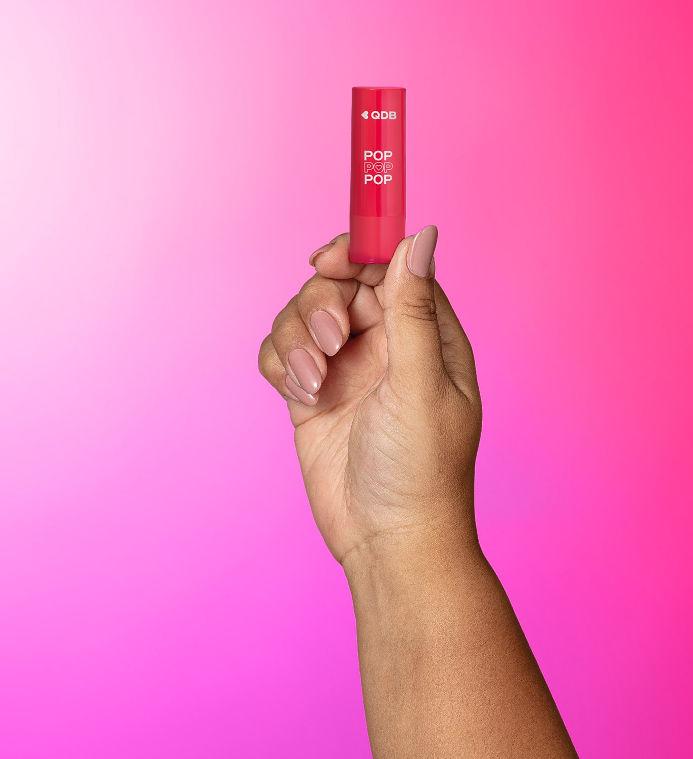 Imagem de uma mão segurando um batom da marca POP Quem Disse, Berenice? em embalagem rosa com letras brancas. O fundo tem um degradê de branco, roxo e rosa.