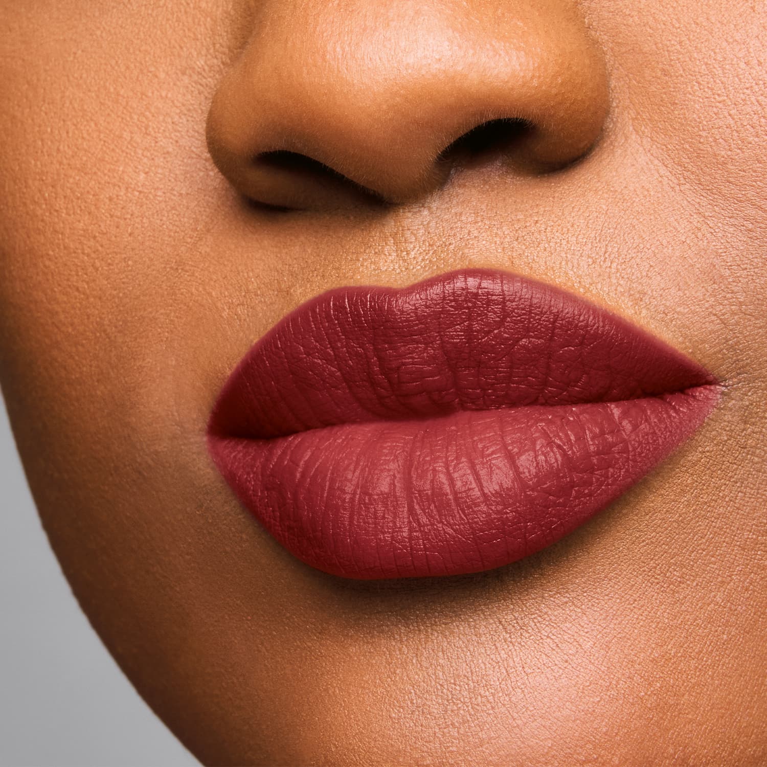 Imagem de um rosto feminino em close-up, evidenciando os lábios com batom cremoso em tonalidade de rosa intenso.