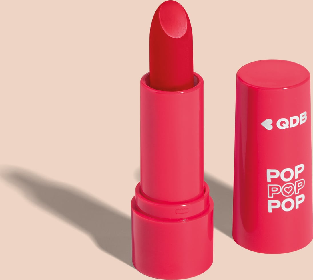 Imagem de um batom semi matte na cor Vermelho Icônico em embalagem rosa vibrante e tampa na mesma tonalidade com letras brancas. O produto faz parte da marca  POP Quem Disse, Berenice?. O fundo da imagem é lilás com sombreado.