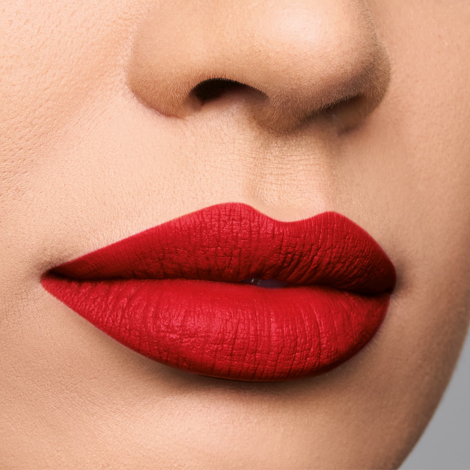 Imagem de um rosto feminino em close-up, evidenciando os lábios com batom semi matte vermelho vibrante.