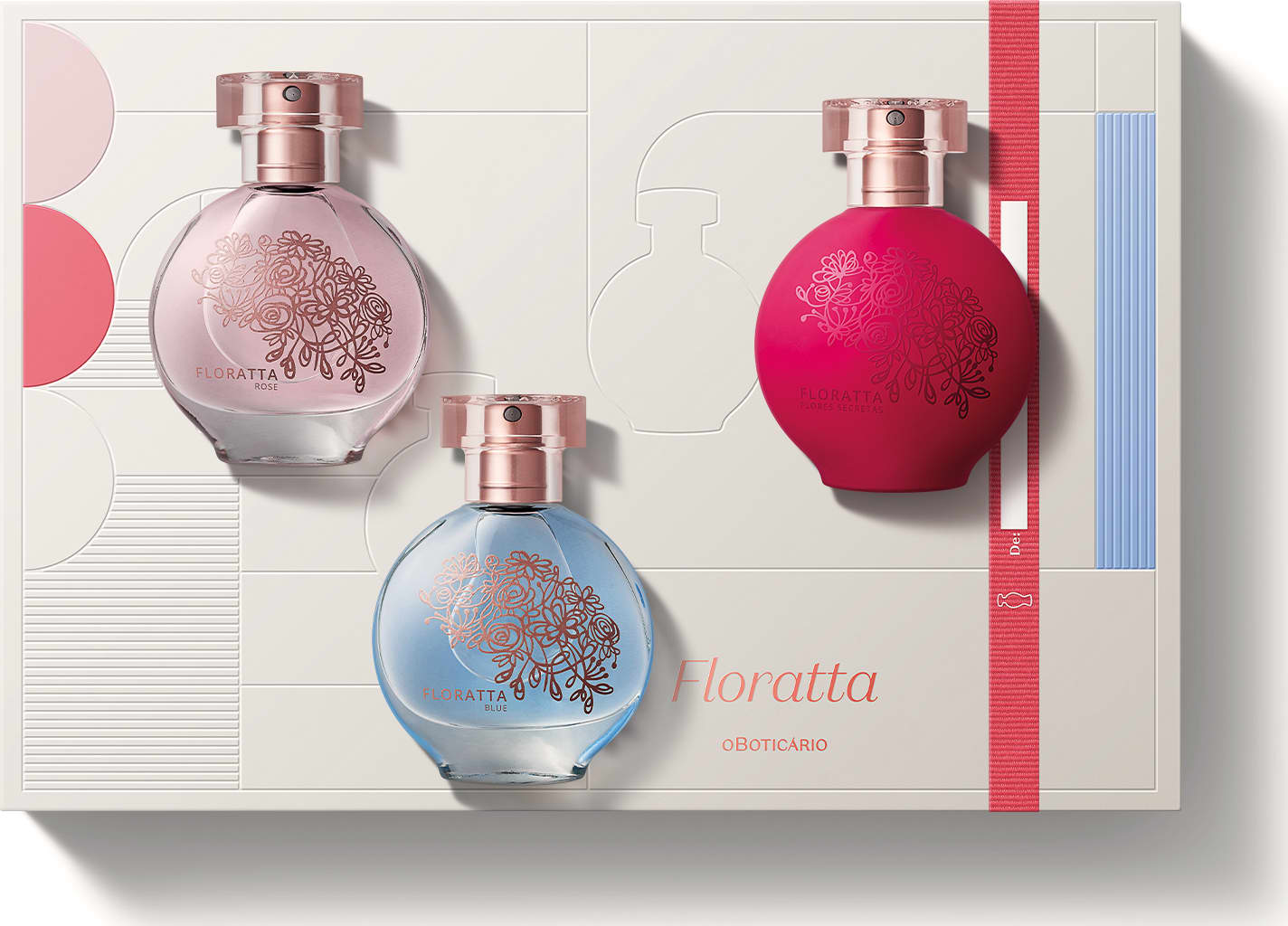 Conjunto de três frascos de perfume Floratta. Frascos de vidro arredondados com detalhes florais gravados, nas cores rosa claro, azul claro e rosa vibrante. Tampas de metal rosado. Embalagem retangular com faixas nas cores correspondentes aos frascos.