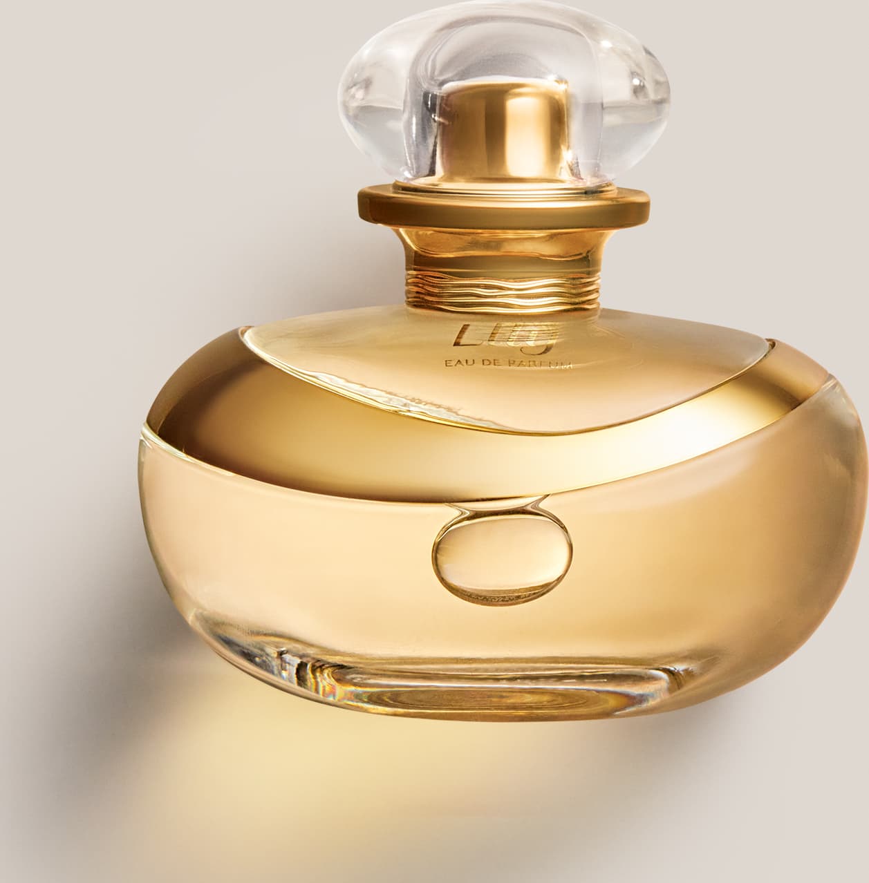 A imagem mostra um frasco de perfume da marca Lily. O frasco tem uma forma orgânica e elegante, com um anel dourado no centro do corpo.