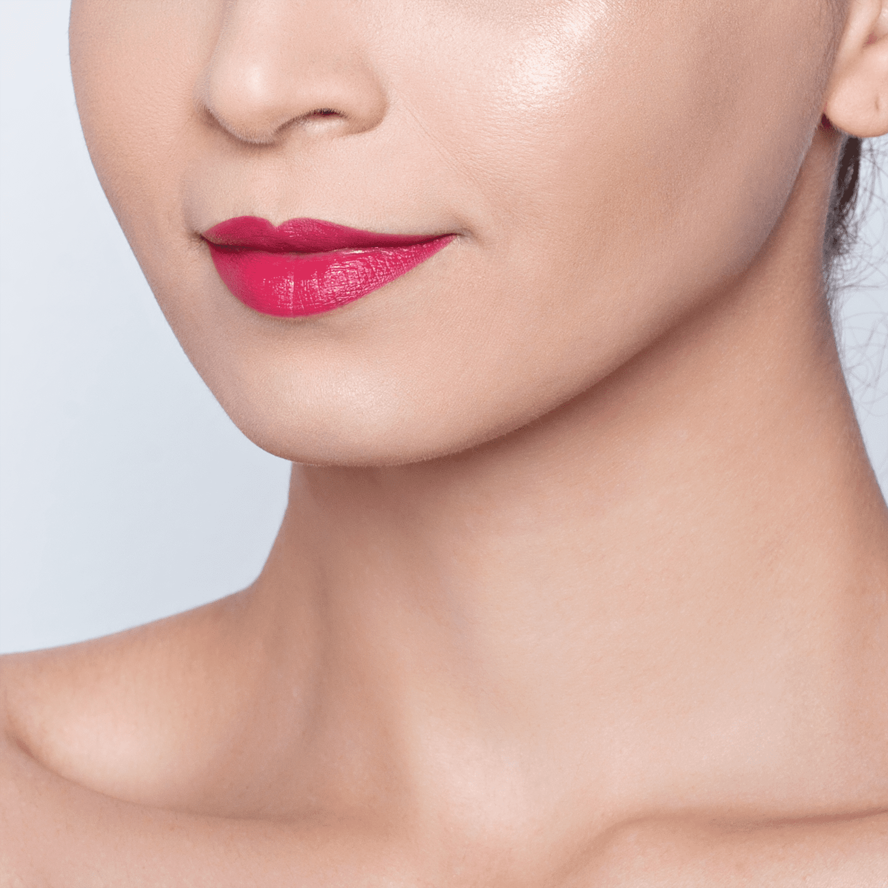 Batom em tom intenso e brilhante. Lábios femininos com aplicação uniforme do produto, realçando a cor e o brilho dos lábios. A imagem foca nos lábios maquiados, mostrando parcialmente o nariz e o queixo da pessoa.
