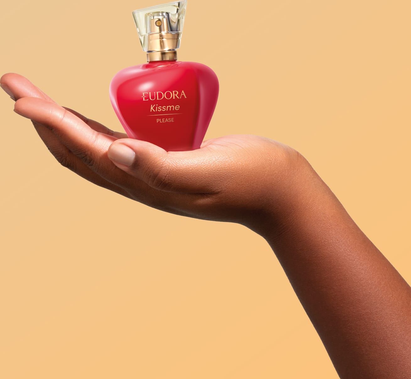 O produto apresentado é um frasco do Desodorante Colônia Kiss Me Please, que está em cima da mão de uma modelo feminina.