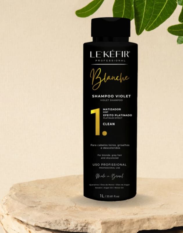 A imagem mostra o frasco do shampoo posicionado junto a longos cabelos loiros espalhados, pertencentes a uma pessoa que não é totalmente visível na foto.