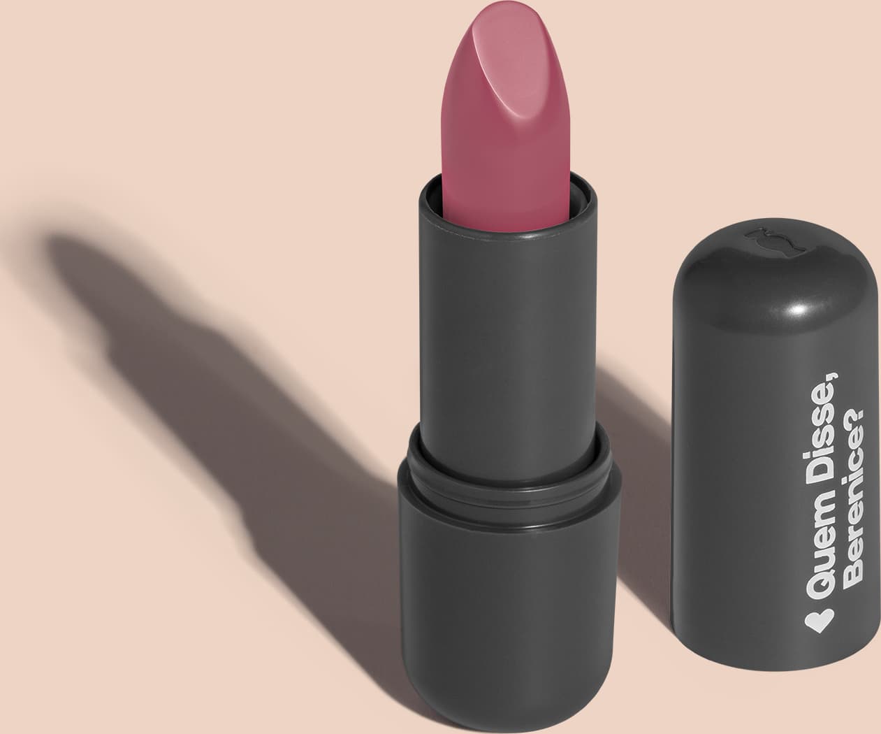 O produto apresentado na imagem é um batom da marca Quem Disse, Berenice?. O batom possui uma embalagem preta e o produto em si é de uma tonalidade rosa. O rótulo da embalagem apresenta o nome da marca "Quem Disse, Berenice?" em letras brancas.