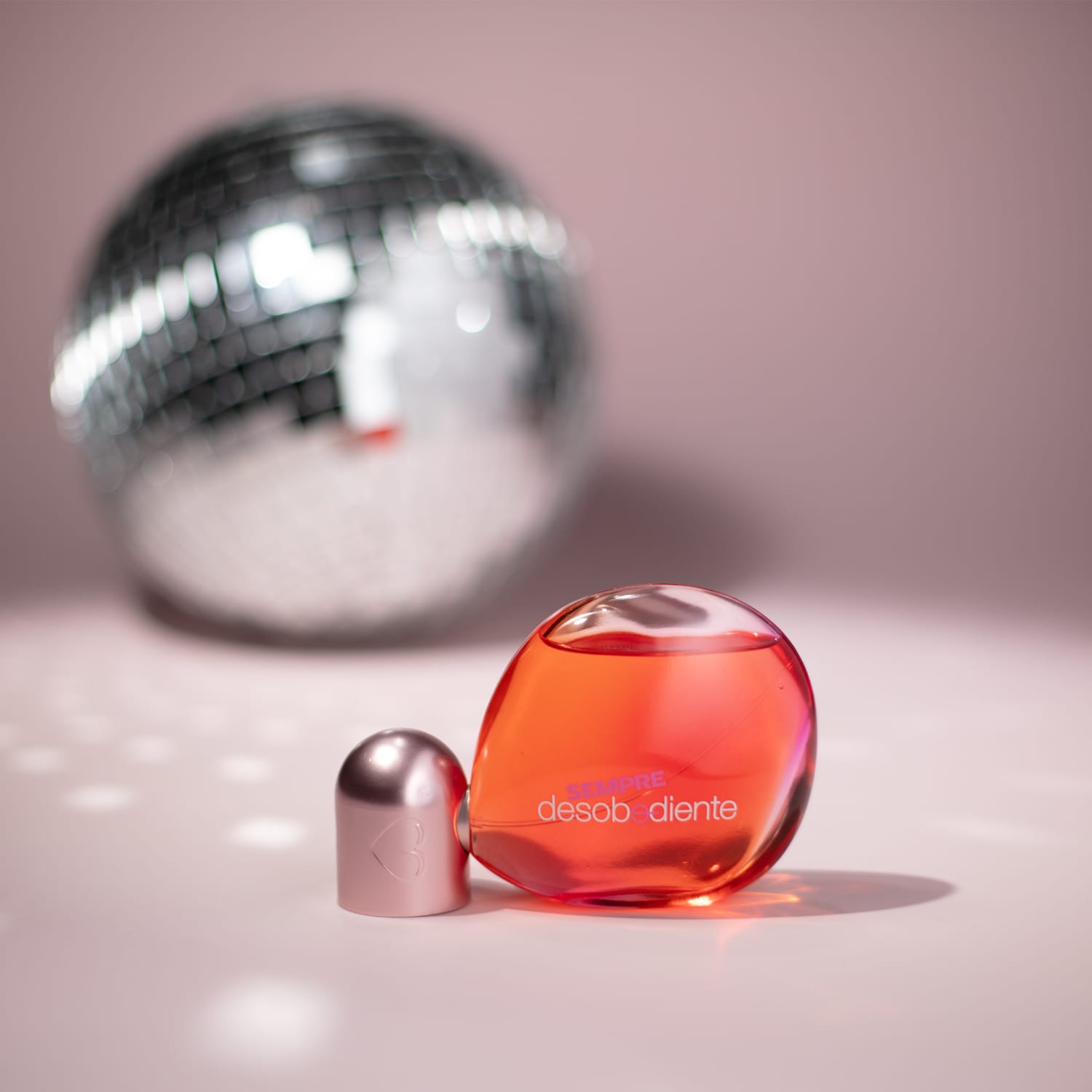 Imagem do perfume com um globo espelhado ao fundo.