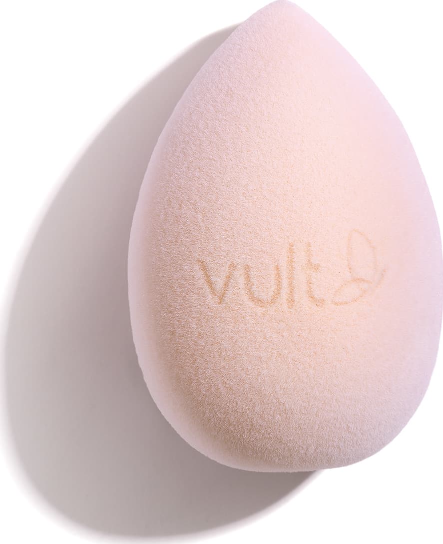 Esponja de maquiagem em formato de gota, com superfície suave e textura aveludada, exibindo o logotipo da marca Vult em sua superfície.