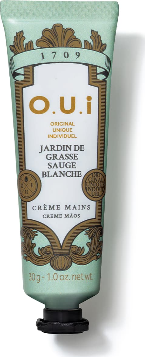 Creme para as mãos da marca O.U.I. em embalagem de tubo verde-claro com detalhes dourados e rótulo com informações sobre o produto "Jardin de Grasse Sauge Blanche".
