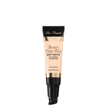 A imagem mostra uma embalagem pequena, sem a tampa, tipo bisnaga, de base líquida, cor muito clara. A embalagem tem detalhes bege e preto, com letra pretas e dourada.