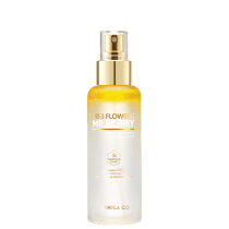 Embalagem cilíndrica pum com deltalhes em branco e dourado. Descrição adicional do produto como "Ampoule In Mist" com extrato de flor e mel, hidratante e nutritivo para a pele. Marca Banila Co. visível na parte inferior.