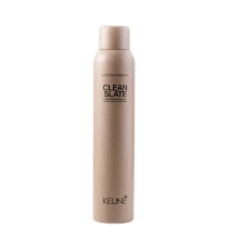 A imagem mostra o shampoo a seco Clean Slate da marca Keune. Frasco cilíndrico na cor bege claro com o texto "CLEAN SLATE" em letras maiúsculas pretas, descrevendo um "shampoo refrescante purificante" abaixo. O logotipo Keune aparece na parte inferior