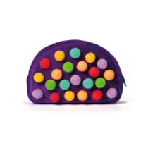 Este é um necessaire maquiagem em formato arredondado, confeccionado em tecido de cor roxa intensa. Sua superfície é totalmente revestida por pequenas bolinhas felpudas multicoloridas, incluindo tons de amarelo, laranja, vermelho, verde, turquesa e lilás.