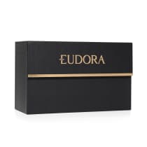 A imagem mostra o porta batom Eudora. A caixa é retangular, preta com textura rendada e o nome "Eudora" está escrito em letras douradas grandes na parte frontal com uma linha dourada horizontal abaixo.