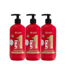 Três frascos de shampoo Revlon Professional, da linha "Uniq One" de 490ml cada. Cada frasco possui uma bomba preta na parte superior. Rótulos com o logotipo da Revlon, o nome do produto e informações como "Shampoo concentrado com 10 benefícios reais".