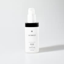 A imagem mostra um frasco branco de plástico contendo um produto da linha Gennezi. O nome "Gennezi" está impresso em letras pretas na parte frontal do frasco. O tamanho do frasco indicado é de 120ml.