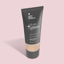 O produto apresentado é uma base líquida da marca Tô no Glow, com embalagem em tubo plástico preto e branco. O rótulo exibe o nome da marca e a descrição "Radiância natural, leveza e conforto". O produto é classificado como "Base líquida".