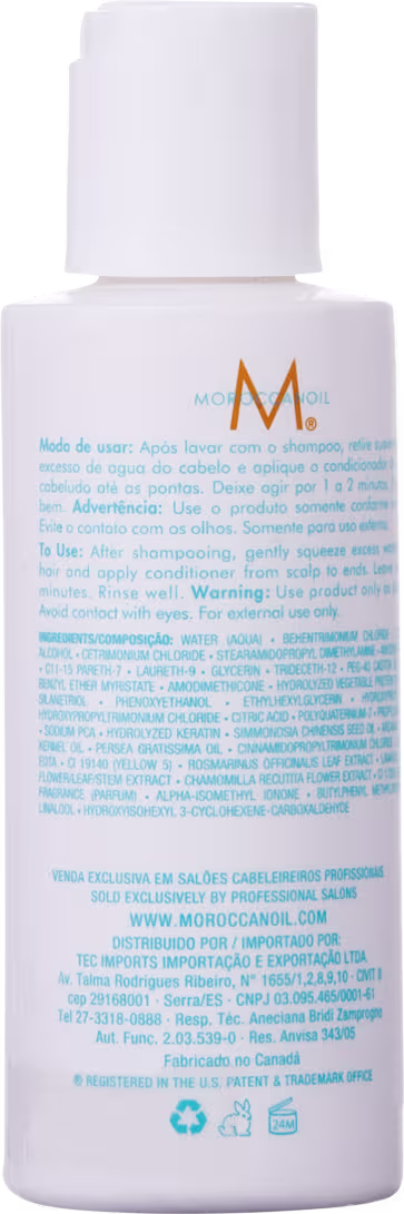 Frasco branco de produto Moroccanoil com rótulo informativo em português. Embalagem cilíndrica com tampa, contendo informações sobre modo de uso e ingredientes.