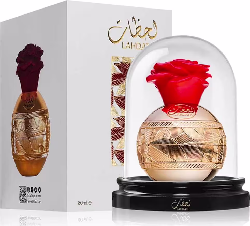 Frasco de perfume Lattafa Lahdath com design dourado e vermelho, contido em uma caixa branca com detalhes dourados. O frasco possui um formato arredondado e uma tampa vermelha em forma de flor.