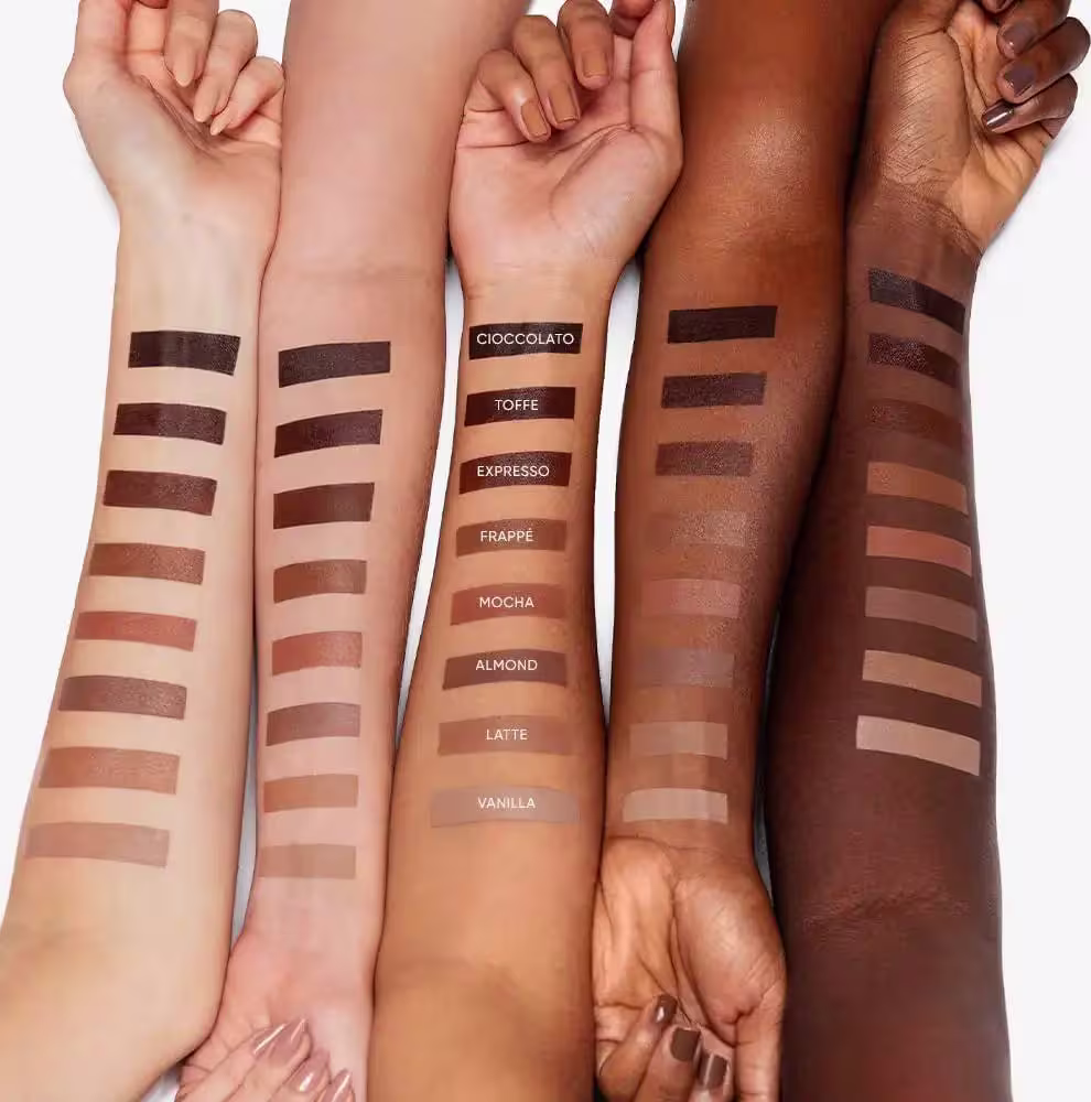 A imagem mostra diferentes tons de pele, com amostras das tonalidades de cores do Shape Stick, como Cioccolato, Toffee, Espresso, Frappe, Mocha, Almond, Latte e Vanilla.