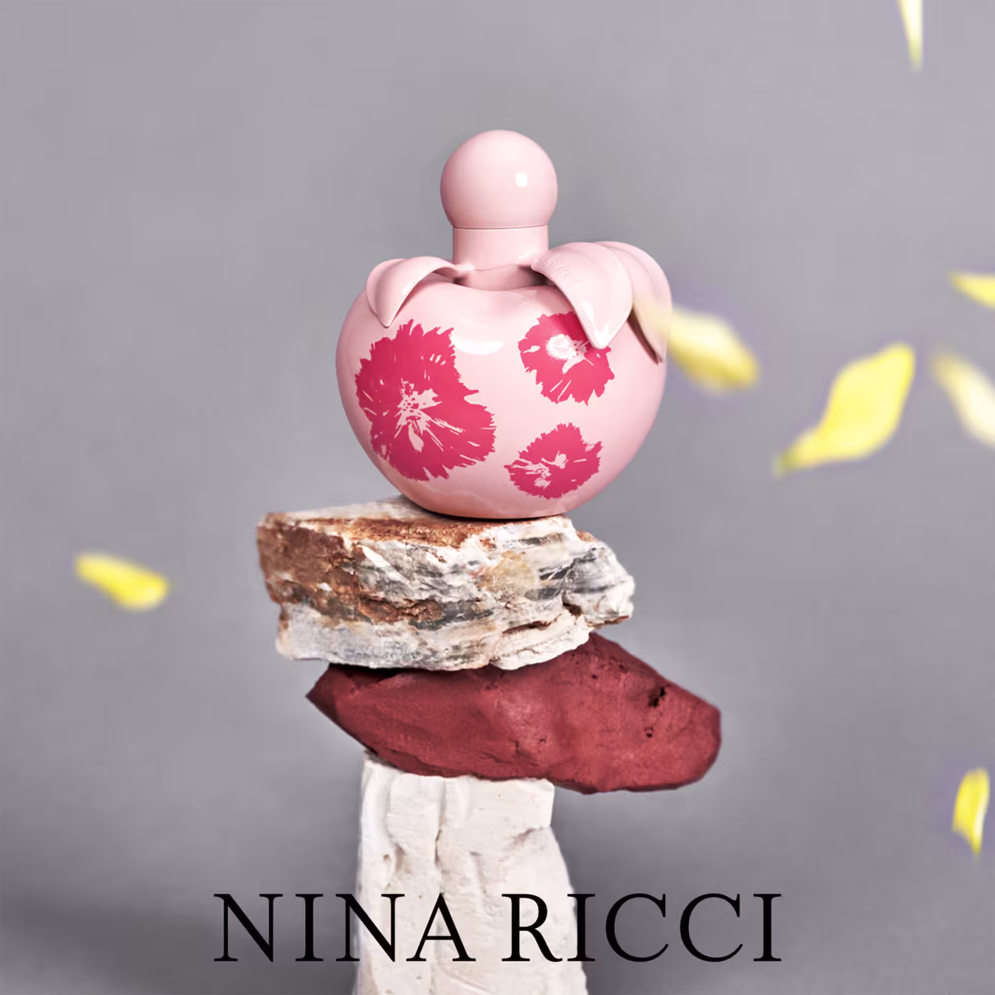 Conjunto de produtos Nina Ricci Nina Fleur. Frasco de perfume transparente em formato de coração com detalhes florais vermelhos. Loção corporal branca em tubo cilíndrico com o nome "Nina Fleur" impresso.
