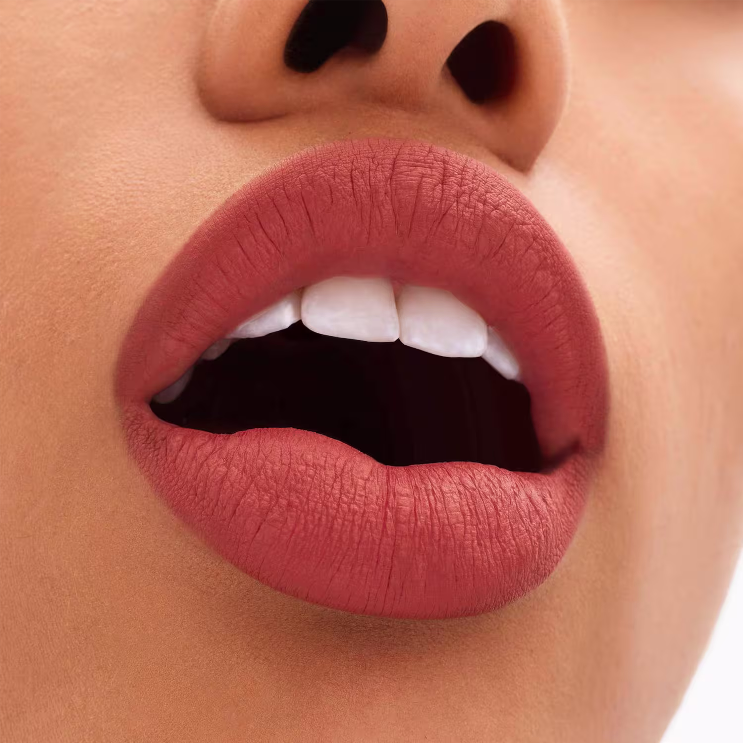 Destaque para os lábios carnudos e bem delineados, exibindo os dentes brancos perfeitos em contraste com a boca entreaberta em um sorriso discreto.