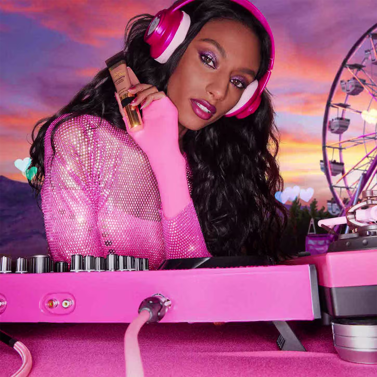 A imagem mostra uma mulher super produzida, com fone de ouvido e uma mesa de dj, ambos de cor rosa, segurando uma embalagem da base próxima ao rosto.