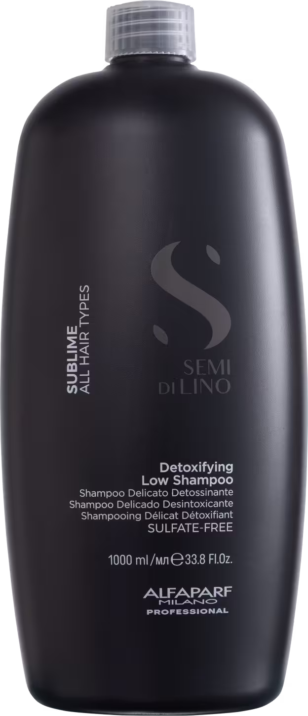 A imagem mostra o shampoo Semi di Lino Sublime Detoxifying Low 1 litro, da marca Alfaparf Milano. Apresenta o rótulo com o nome Semi di Lino - Detoxifying Low Shampoo.  A embalagem preta com o logo e informações em branco dá um visual sofisticado.