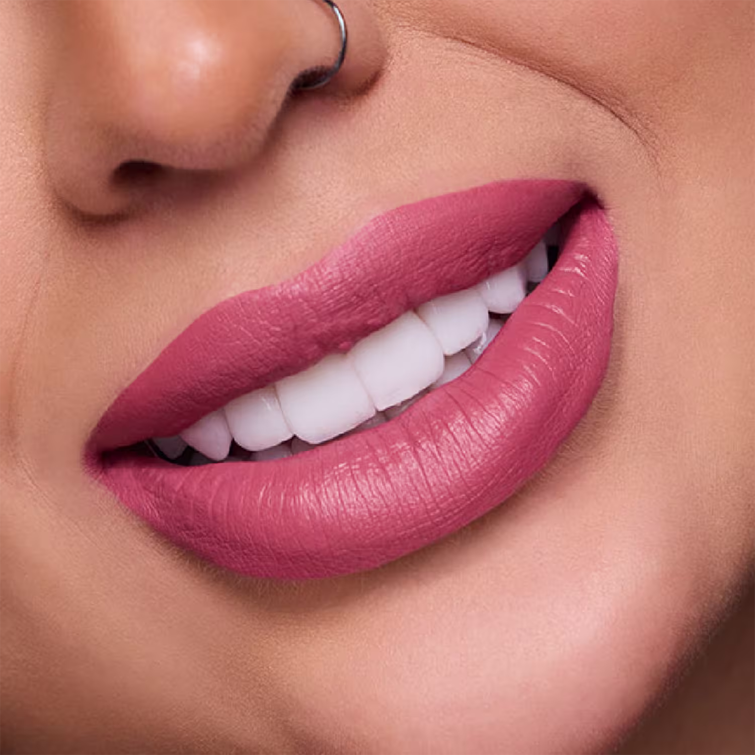 A imagem mostra um close nos lábios carnudos e bem delineados de uma mulher branca. Os lábios estão cobertos com o batom de tom rosa claro e mate, que realça a textura e o volume natural dos lábios.