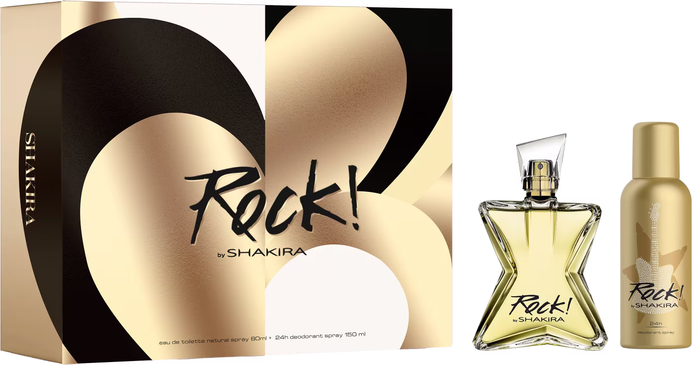 Conjunto de produtos de perfumaria da marca Shakira. Inclui um frasco de perfume em formato triangular com líquido dourado, uma caixa preta e dourada com o nome "Rock!" em letras cursivas, e um frasco menor de desodorante spray na mesma tonalidade dourada