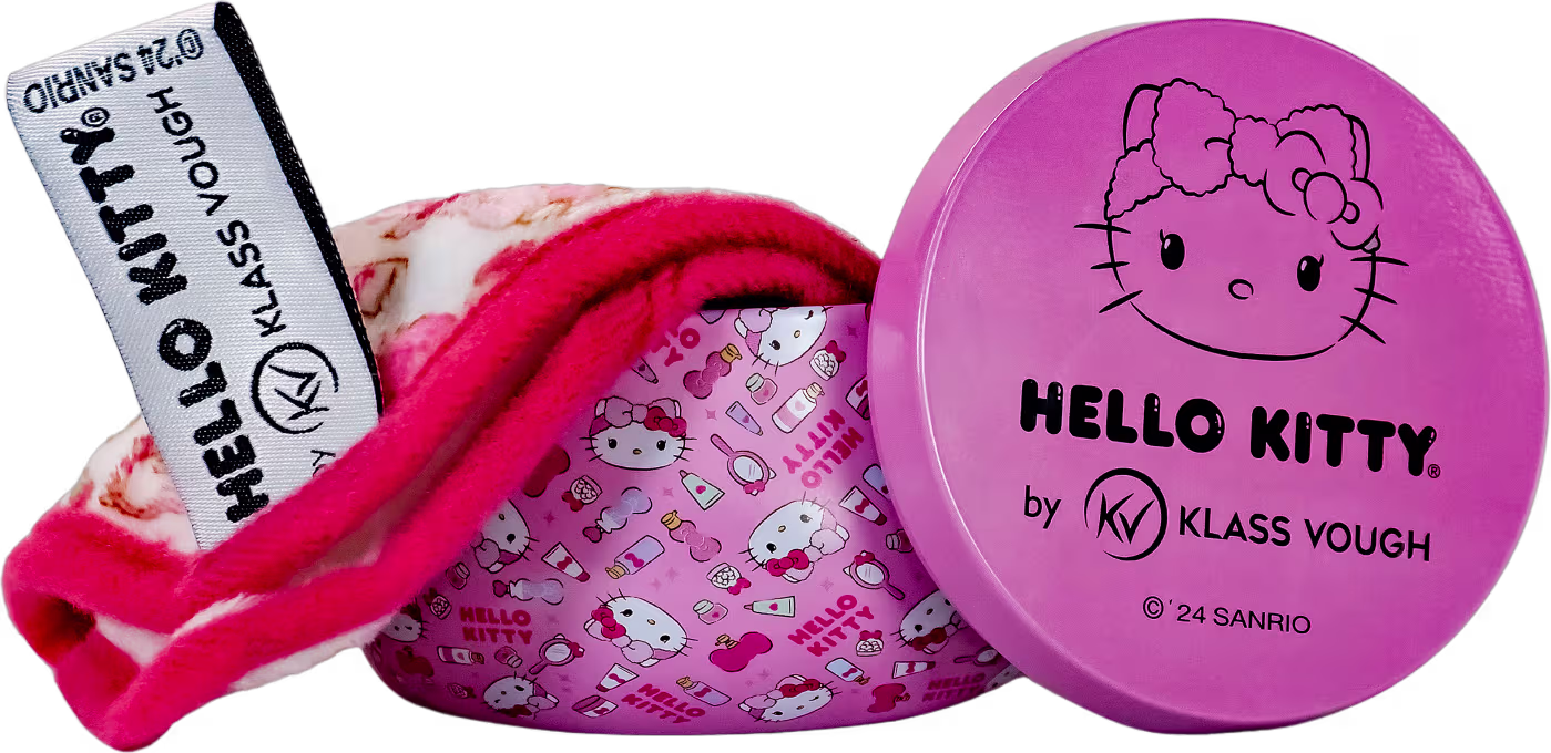 A imagem mostra uma embalagem redonda compacta rosa com o rosto da personagem Hello Kitty estampado com estojo cilíndrico aberto onde é possível ver a toalha demaquilante. Tudo com ilustrações da Hello Kitty e acessórios de beleza.