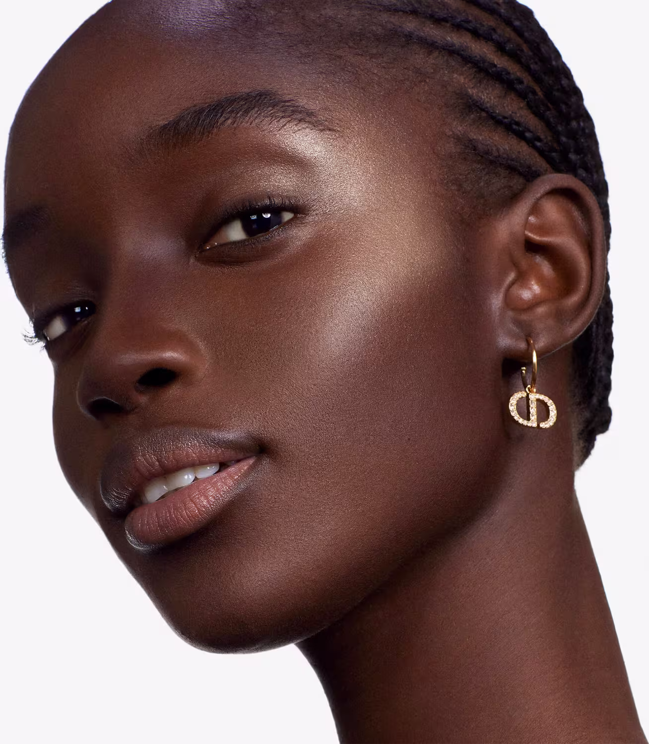 Esta imagem mostra uma modelo negra com uma pele brilhante e maquiagem impecável. Ela tem olhos escuros e expressivos, realçados por maquiagem preta, e lábios cheios com um batom nude.