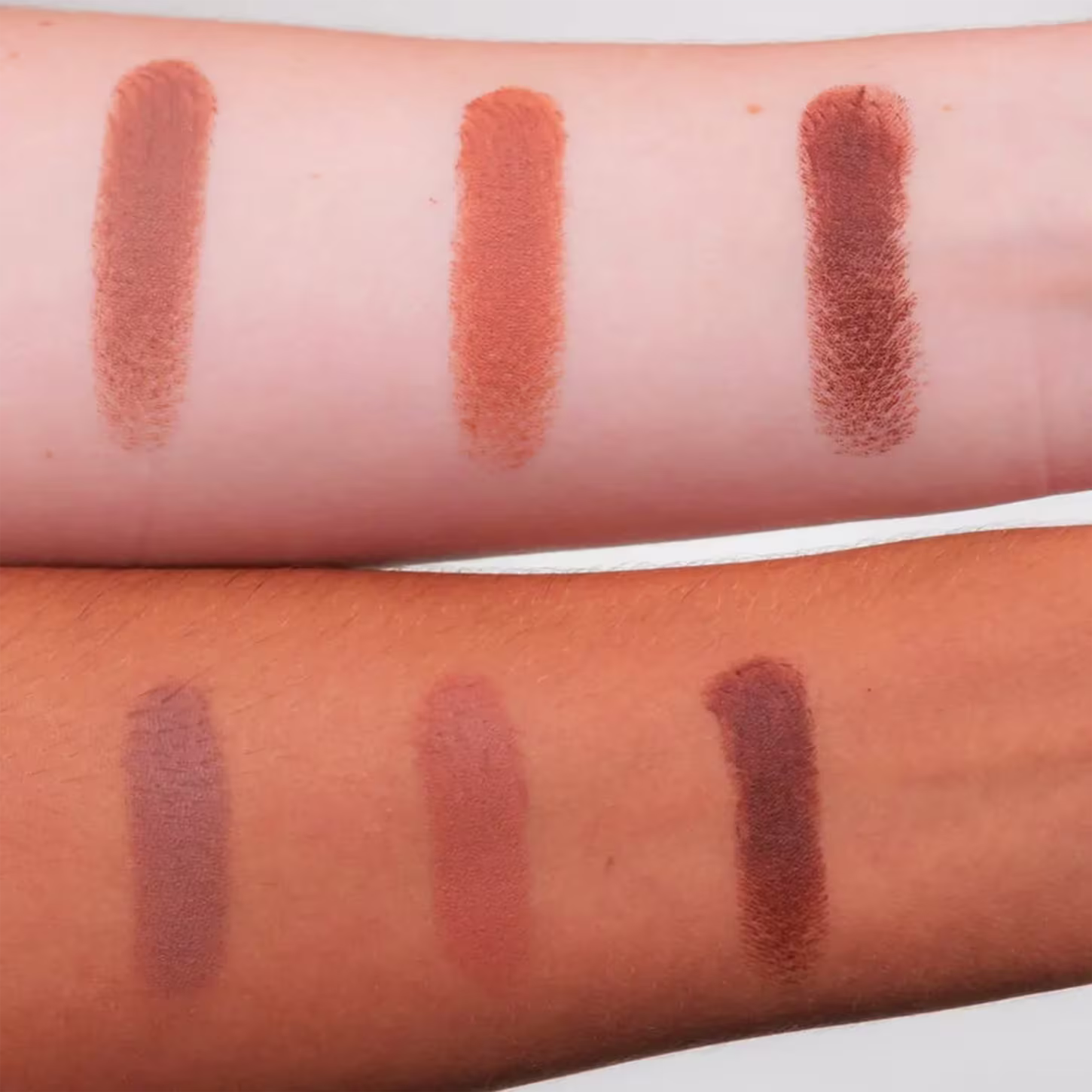 A imagem apresenta três amostras das cores do contorno em diferentes tonalidades de pele. Cada amostra é apresentada como uma faixa alongada e estão dispostas lado a lado sobre o antebraço, mostrando o resultado da cor.