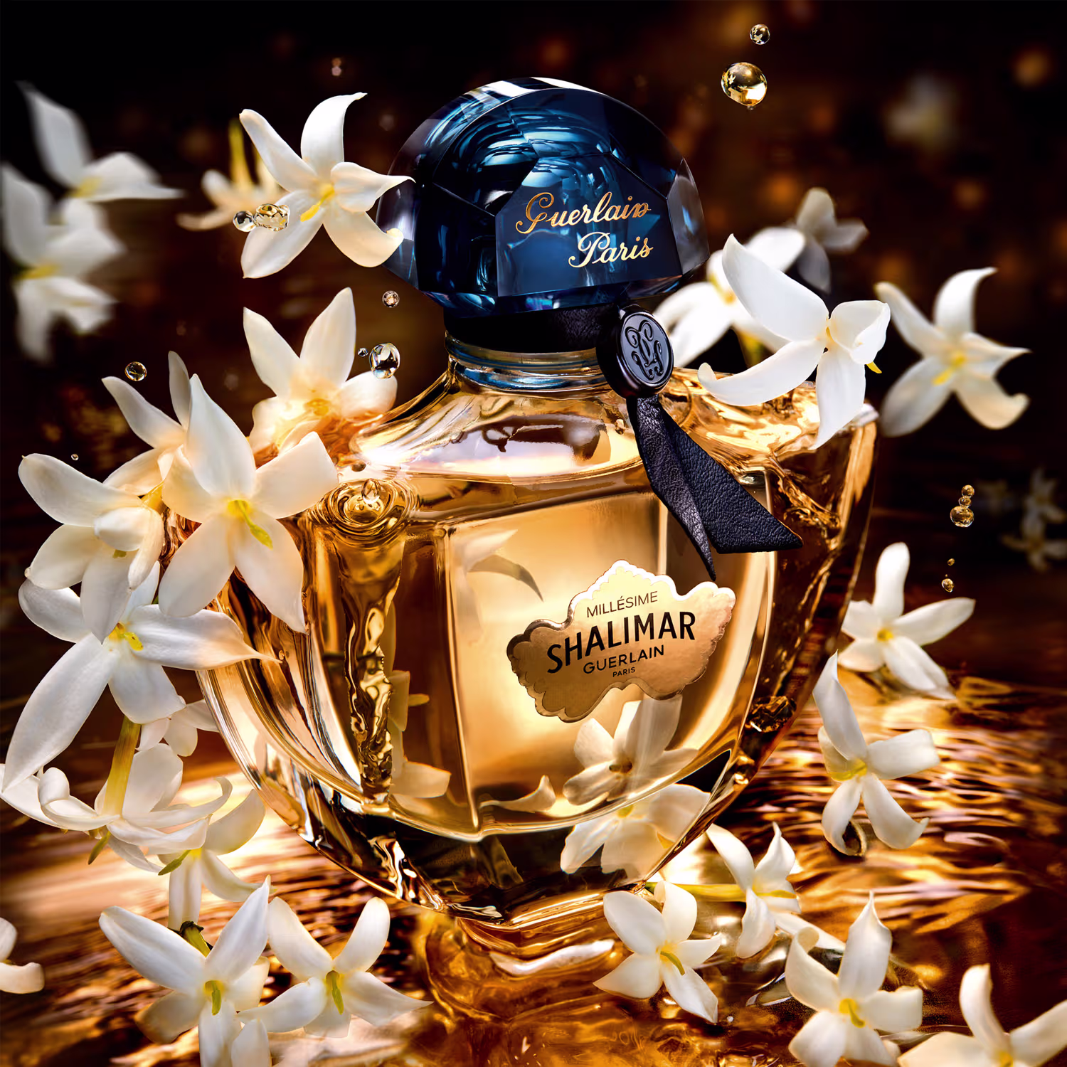 A imagem mostra um frasco de perfume arredondado com tampa azul, com um fundo de flores brancas.