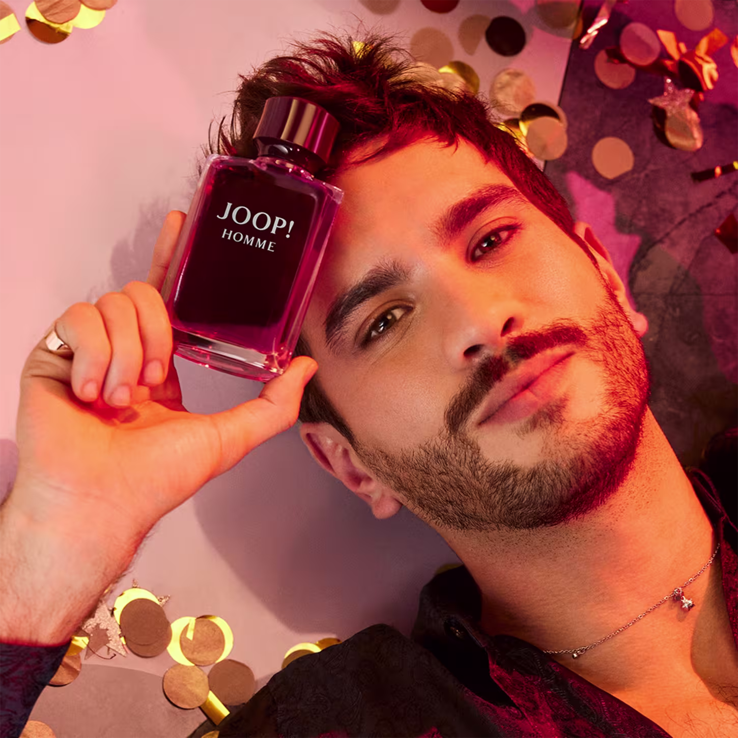 A imagem mostra um homem segurando o frasco do perfume.