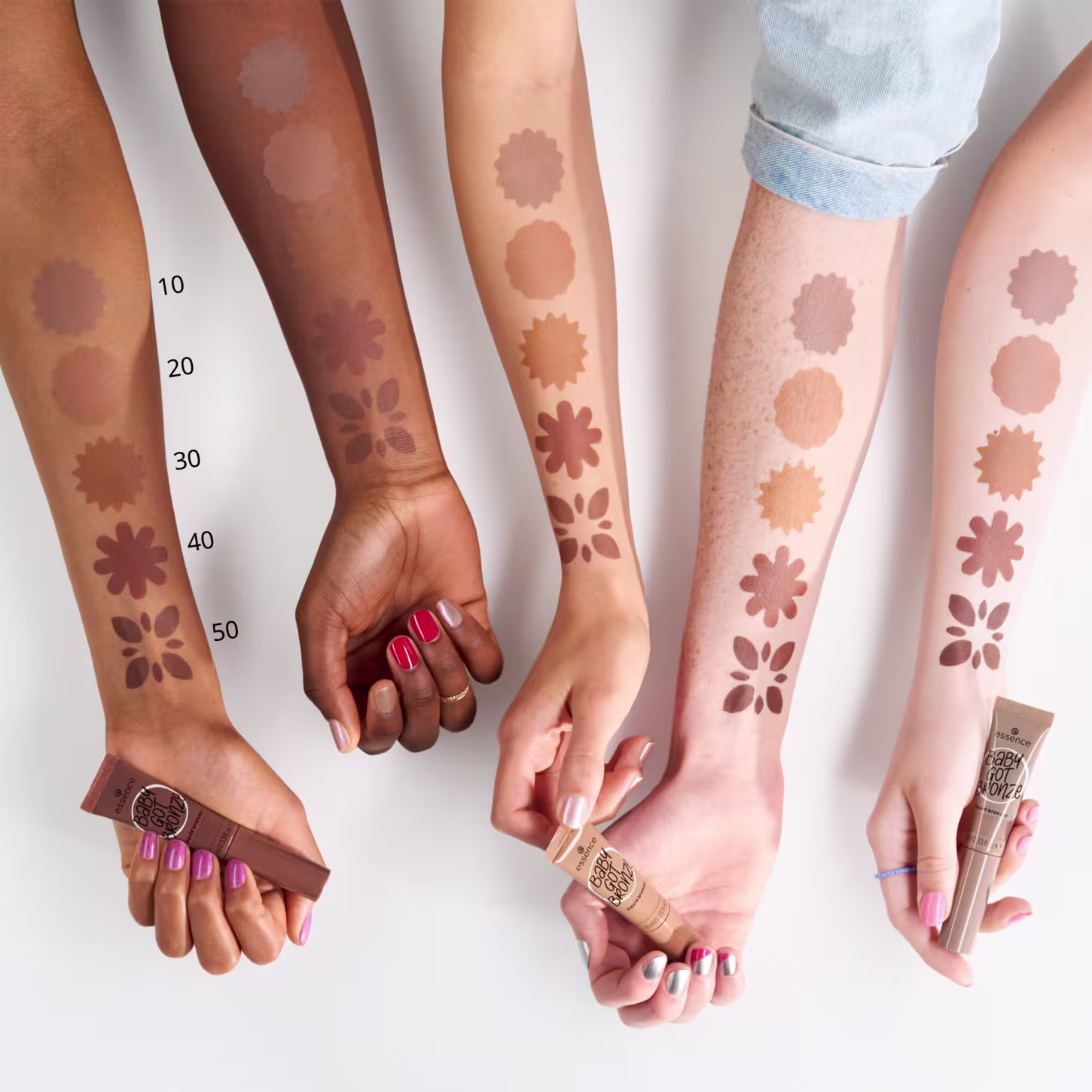 4 braços de pessoas com cor de pele distintas. Eles estão pintadas com as três cores disponíveis na paleta para demonstrar como cada tom fica em diferentes peles.