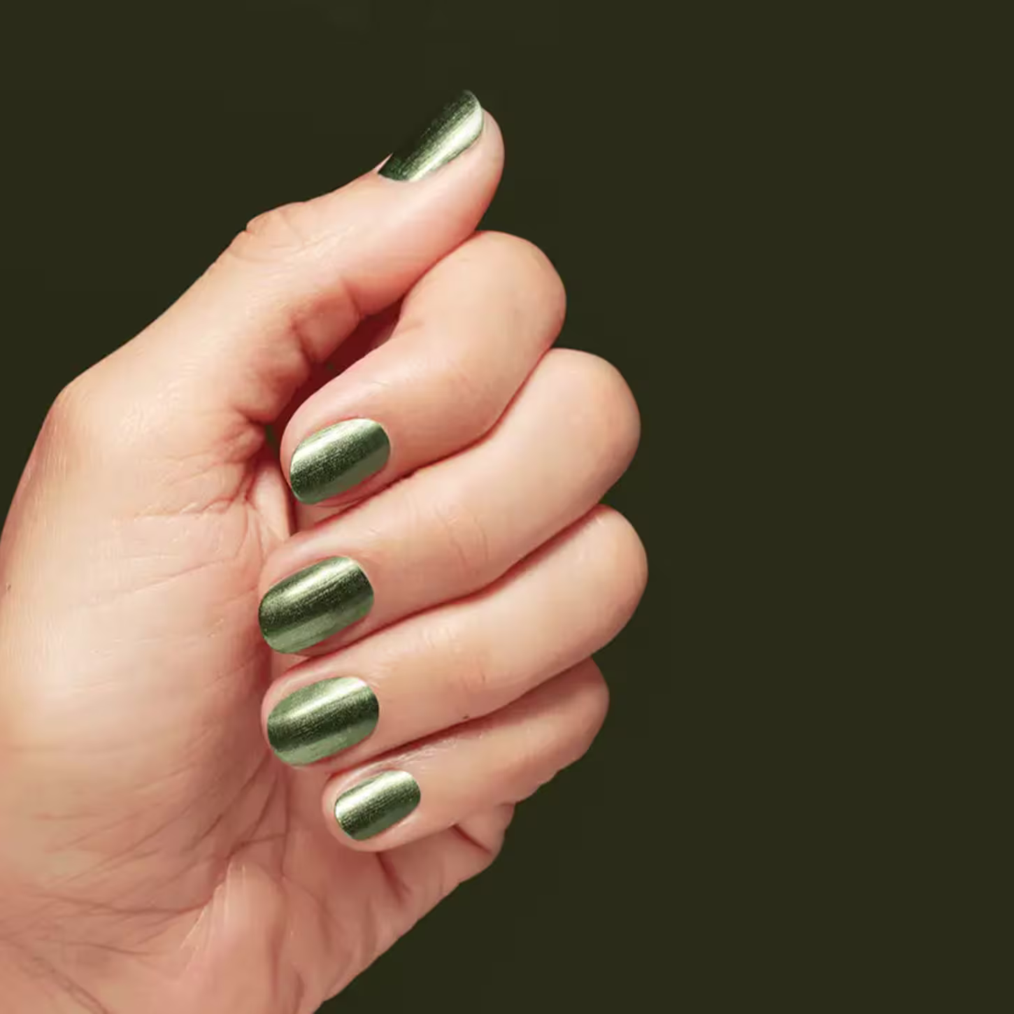 Uma mão feminina pintada com o esmalte. Fundo verde.