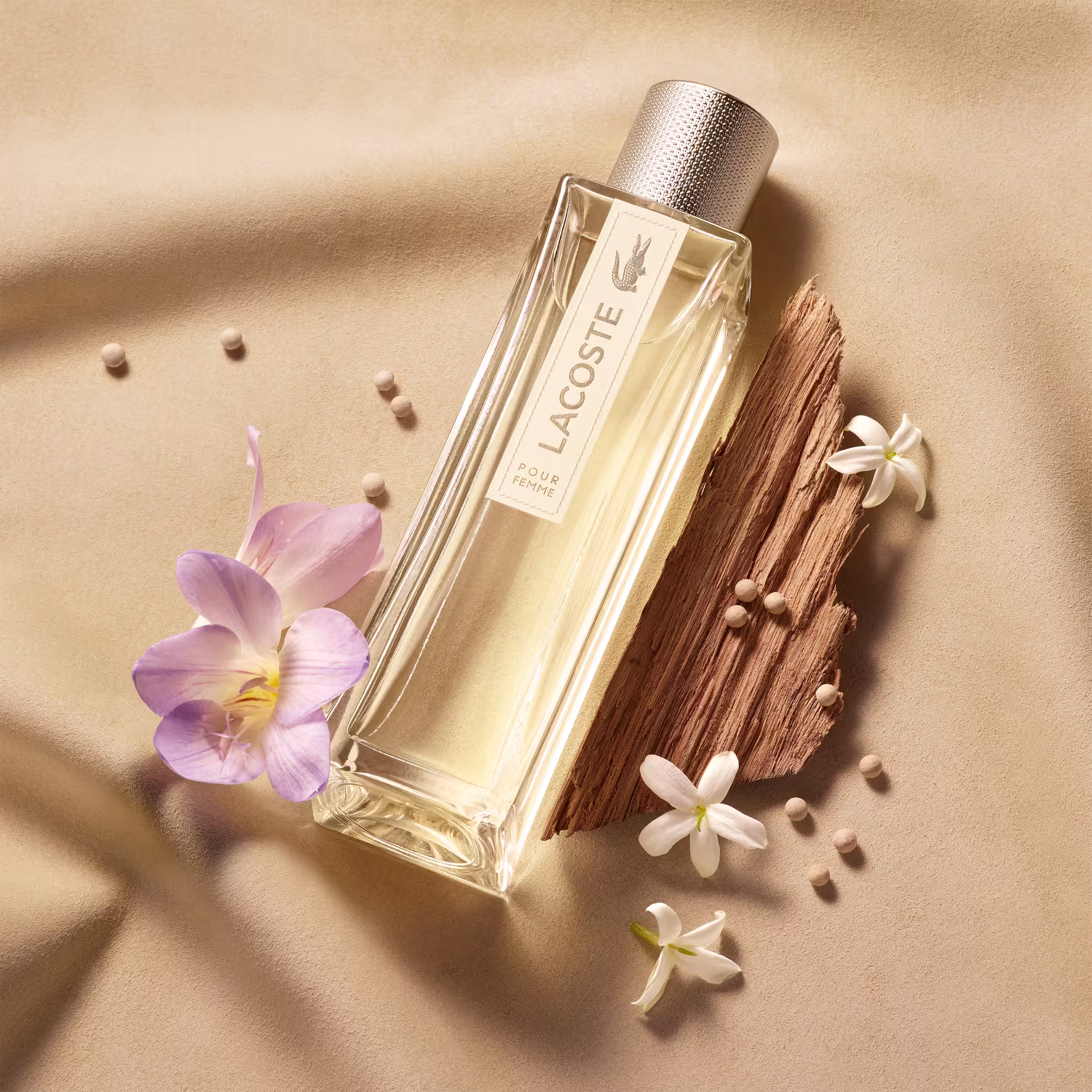 Perfume feminino Lacoste Pour Femme. Frasco retangular transparente contendo líquido bege claro. Tampa cilíndrica texturizada na cor bege.