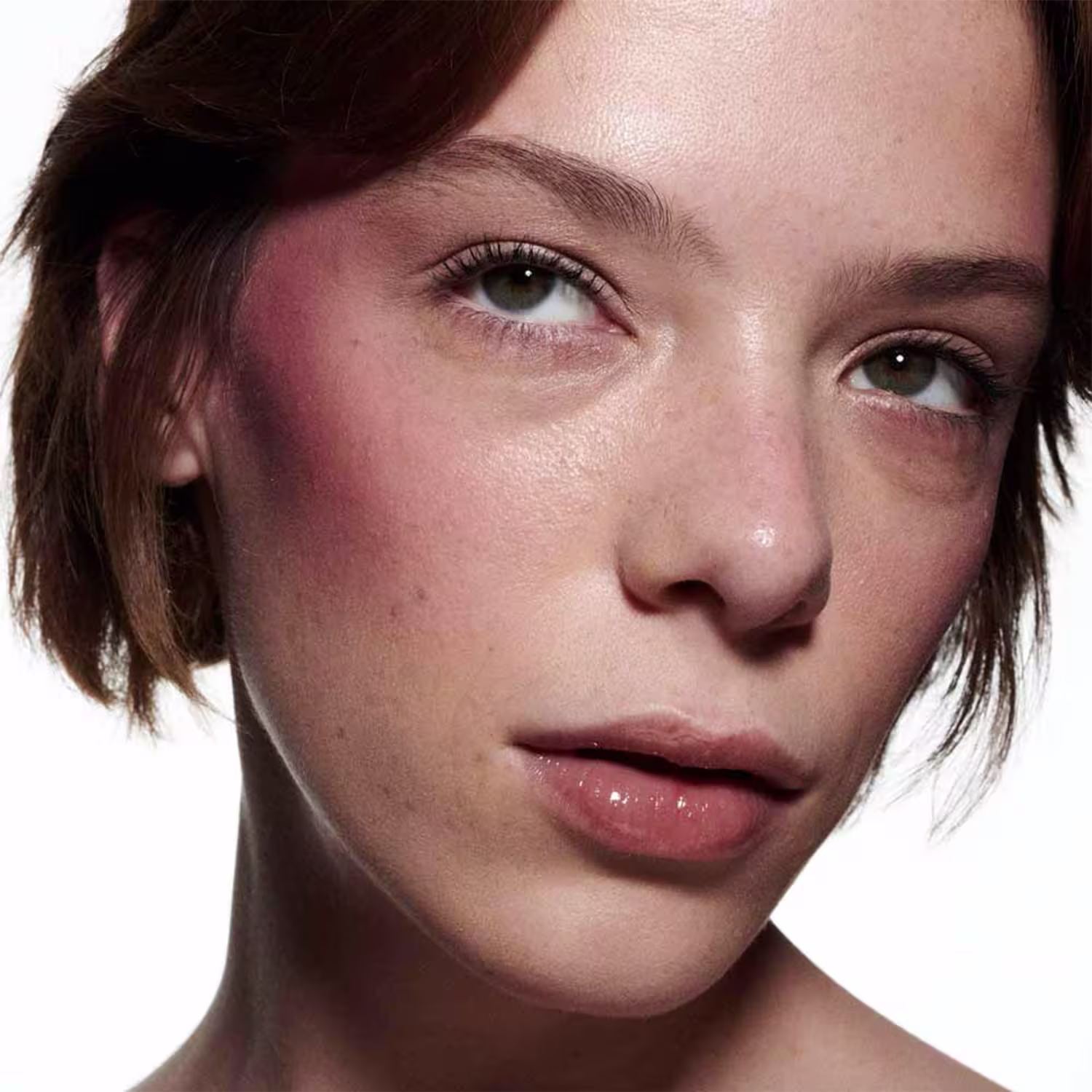 A imagem mostra uma modelo de pele branca e o efeito de cor do Blush Líquido M·A·C Strobe Magic Aura