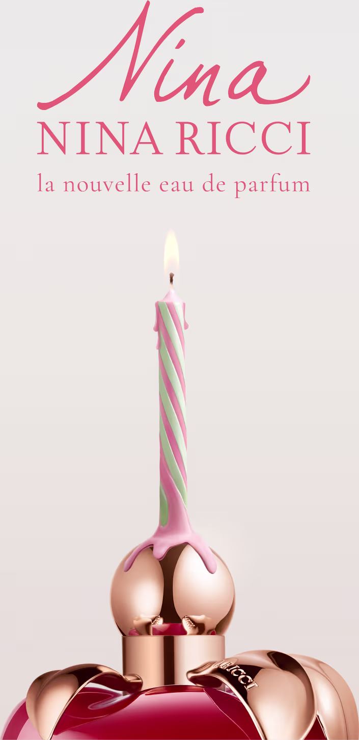 Frasco de perfume em formato de maça, com tampa dourada, em cor vermelha brilhante. Rótulo com nome da marca "Nina Ricci" visível.