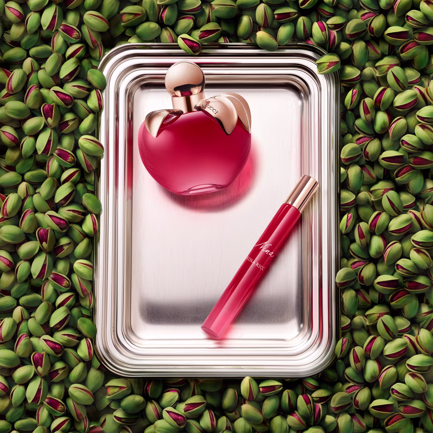 Frasco de perfume em formato de maça, com tampa dourada, em cor vermelha brilhante. Rótulo com nome da marca "Nina Ricci" visível.